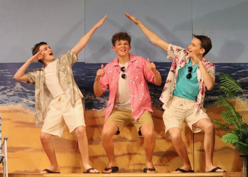 Three actors posing on stage in Much Ado About Nothing